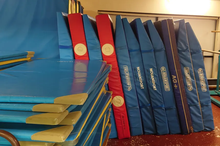 Tapis de parade bleus et rouges alignés contre le mur du gymnase