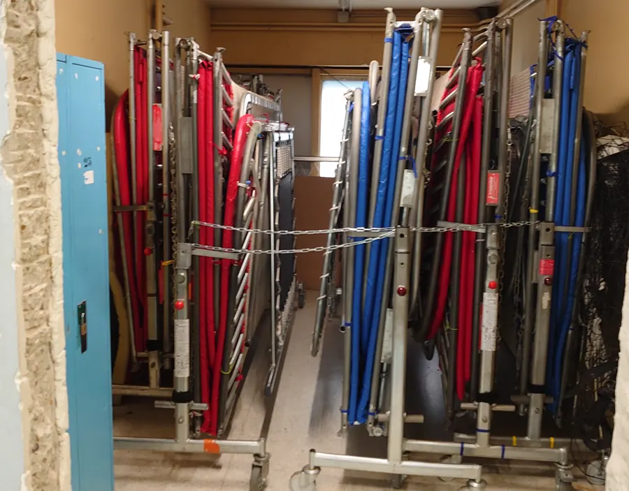 Les trampolines du club, pliés sur leurs chariots à roulettes dans le local de rangement